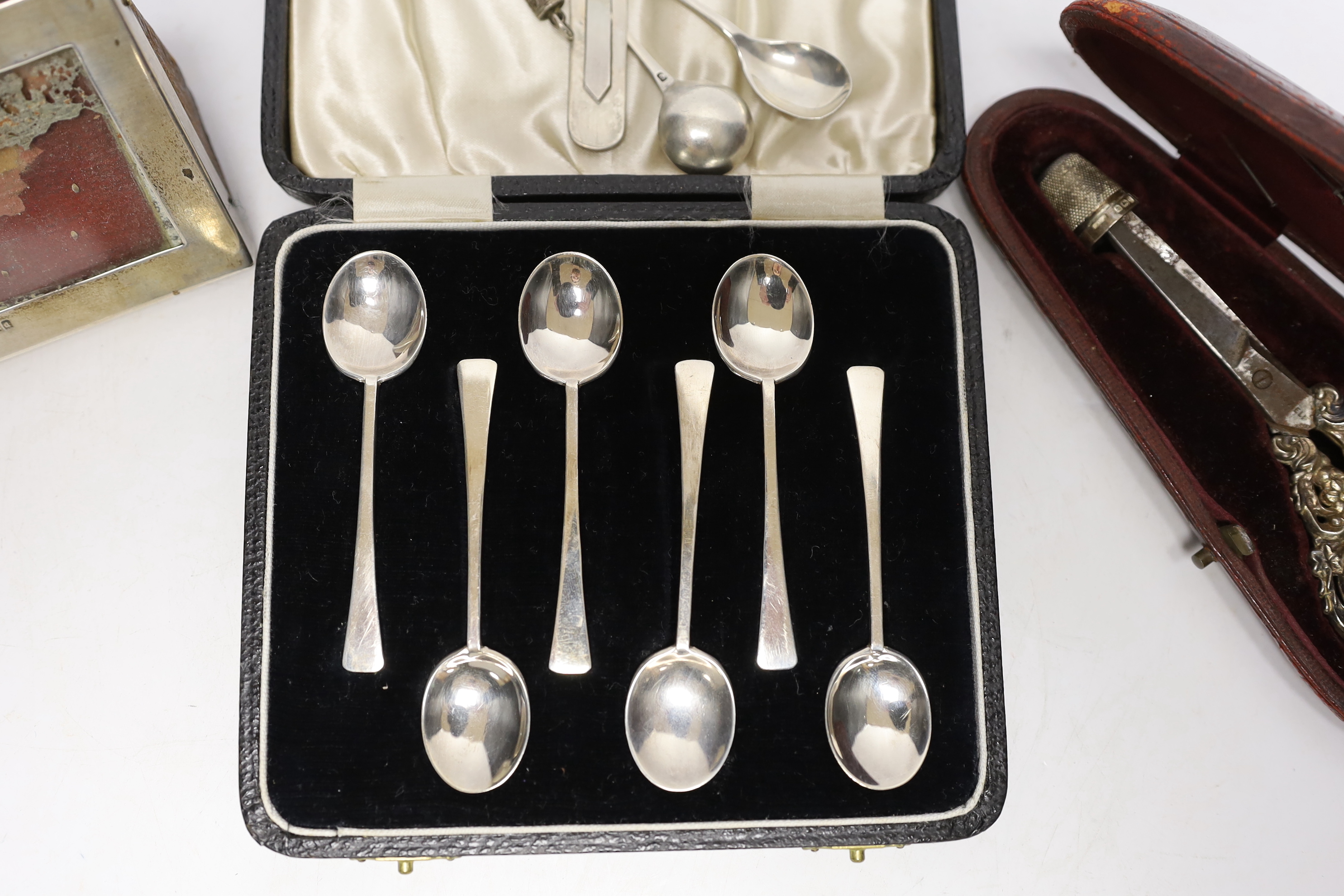 A cased pair of late Victorian repousse silver handled scissors and later silver thimble, a silver mounted photograph frame, cased set of six silver coffee spoons, bookmark, penknife and two condiment spoons.